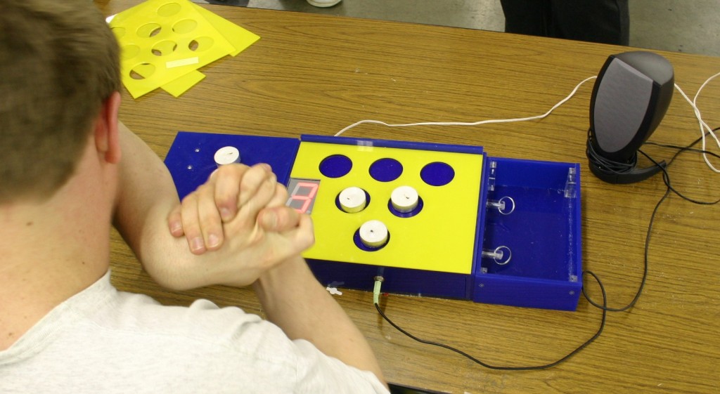 Figure 2: Client using the C-pad. The LED indicator displays the current count of 3 tea lights on the template. A 6 position template is currently being used, and additional templates of 3 and 8 are in the upper left corner of this photo.