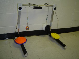 Figure 2: the Play Station device, showing two pull switches hanging from the crossbar, two push switches on the base, and the MP3 player and speakers mounted to the crossbar. The entire upper portion can telescope to varying heights and rotate to different angles.