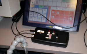 Figure 1. The switch relay device is attached to a PC and to a communication device. The client can use the same switch to activate the device or toggle control between the two devices.