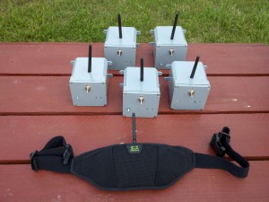 Figure 1: The five radio beacons, with speakers mounted inside, that get mounted on weaving poles, and one radio detector that is worn by the use on a hip belt.