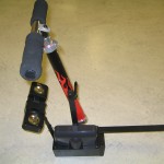 Figure 1: Photo of the device. It mounts to the client’s wheelchair by slipping the horizontal bar on the right side of the photo under the seat cushion. The client grabs the handles with both hands and pulls and releases the handlebar to count. The battery-powered circuitry is mounted in the black box at the bottom of the photo, and audio feedback is provided through the two speakers.