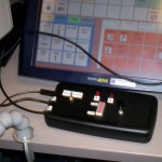 Figure 1. The switch relay device is attached to a PC and to a communication device. The client can use the same switch to activate the device or toggle control between the two devices.